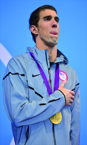 Michael Phelps poses on the podium with the gold medal on Tuesday. Photo: AFP