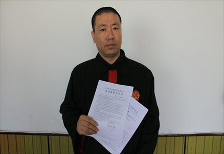 Guo Xuehong, in his former judge's robe, displays on November 29, 2012 local police's notice to send him to a reeducation-through-labor camp. Photo: CFP