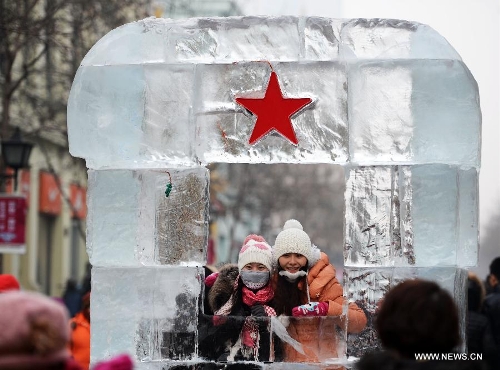 Citizens pose for photos at an ice statue in Harbin, capital of northeast China's Heilongjiang Province, Jan. 20, 2013. The temperature rise in Harbin enabled citizens to play with snow and ice in the outdoors. (Xinhua/Wang Kai) 