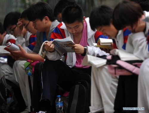 Examinees of national college entrance exam review books as waiting for entering exam rooms at the Dongzhimen Middle School in Beijing, capital of China, June 7, 2013. Some 9.12 million applicants are expected to sit this year's college entrance exam on June 7 and 8. (Xinhua/Gong Lei) 