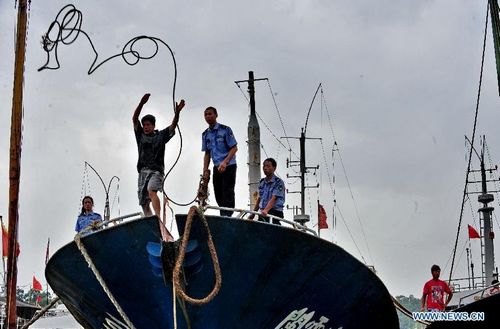 Local officers help fisherman reinforce boats at the Shacheng harbor in Fuding, East China's Fujian Province, August 2, 2012. Typhoon Saola is expected to land on the coast of Zhejiang and Fujian provinces Thursday night or Friday morning. The Fujian flood control headquarters launched a level two emergency response on Wednesday to cope with the typhoon. Photo: Xinhua