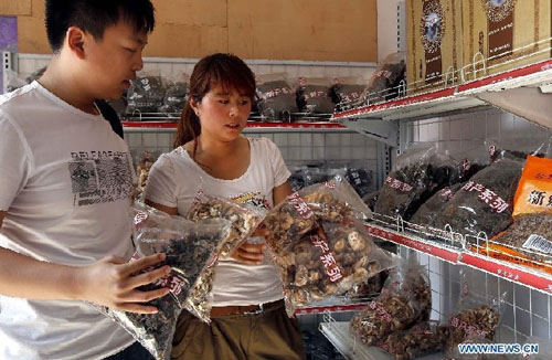 A woman introduces native products to a tourist at Huilong Village in the Taihang Moutains in Huixian County, central China's Henan Province, June 14, 2012. Huilong Village was a poor residential area in the early 1990s. In 2000, an eight-kilometer highway and tunnels of a total length of 1,000 meters were built on the cliffs for the village's development. The village took the advantage of its mountainous scenery to develop tourism industry, increasing the residents' incomes and improving their life. Photo: Xinhua