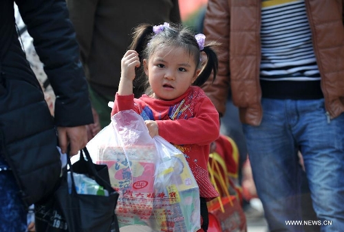 A little girl helps her family carry food at Nanning train station in Nanning, capital of south China's Guangxi Zhuang Autonomous Region, Feb. 3, 2013. Many children travel with their families during the 40-day Spring Festival travel rush which started on Jan. 26. The Spring Festival, which falls on Feb. 10 this year, is traditionally the most important holiday of the Chinese people.Public transportation is expected to accommodate about 3.41 billion travelers nationwide during the holiday, including 225 million railway passengers. (Xinhua/Zhou Hua)