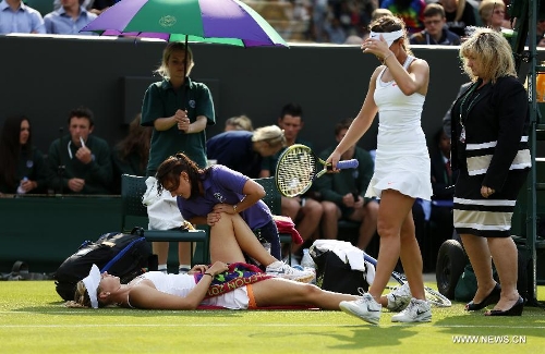 Maria Sharapova of Russia receives medical treatment during the second round of women's singles against Michelle Larcher De Brito of Portugal on day 3 of the Wimbledon Lawn Tennis Championships at the All England Lawn Tennis and Croquet Club in London, Britain on June 26, 2013. Maria Sharapova lost 0-2. (Xinhua/Wang Lili) 