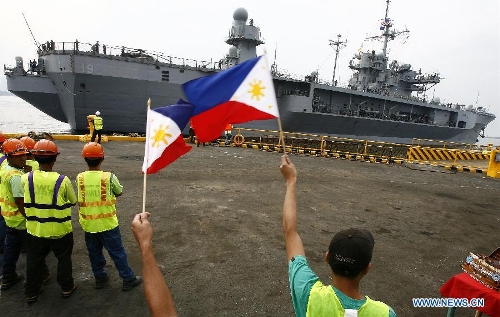 Port workers wave the Philippine flags to welcome the USS Blue Ridge (LCC-19) as it docks in Manila, the Philippines, March 7, 2013. The USS Blue Ridge, flagship for the Commander of the U.S. Navy's 7th Fleet, started a four-day goodwill visit to Manila on Thursday. (Xinhua/Rouelle Umali)  