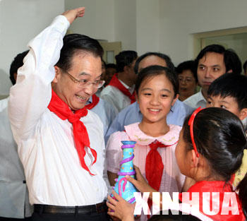 Chinese Premier Wen Jiabao, with a red scarf -- symbol of the official children's organization the Young Pioneers -- around his neck, salutes back as a student presents him a gift during his visit to Shijia Elementary School in Beijing May 31, 2006 to mark the coming Children's day. (Xinhua File Photo)