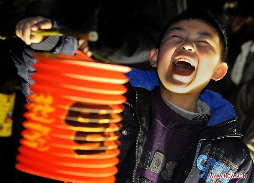  A child laughs with pleasure as he holds a newly-bought festive lantern in Zhengzhou, capital of central China's Henan Province, Feb. 1, 2011. Chinese children are usually given festive lanterns to celebrate the Spring Festival or Chinese Lunar New Year. (Xinhua/Wang Song)