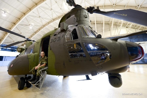 A soldier sits on a new CH-147F Chinook helicopter during the unveiling ceremony in Ottawa June 27, 2013. The 15 newly purchased F-model Chinooks will be engaged in support, domestic and foreign operations for the Royal Canadian Air Force's reactivated 