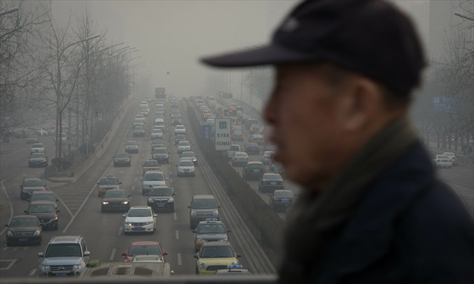 A man crosses a bridge amid heavy traffic and pollution in Beijing on Tuesday. Beijing has the worst traffic jams in the world, as record traffic levels take their toll on people's health, productivity and social lives, a study by IBM reported early January. Beijing and Mexico City scored 99 out of 100 in IBM's commuter pain index, followed by Johannesburg, Moscow and New Delhi. Photo: AFP