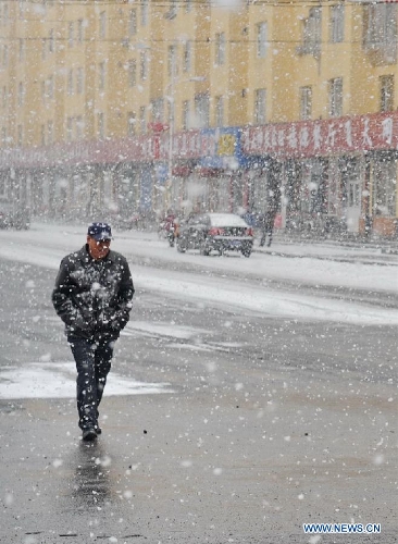 A citizen walks in snow in Baishan City, northeast China's Jilin Province, April 9, 2013. (Xinhua/Zhang Nan) 