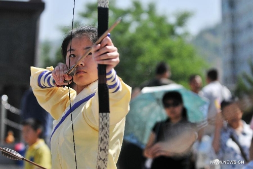 Wang Yawen, who is fond of the Han Chinese culture, performs traditional archery during a celebration activity of the Dragon Boat Festival, in Lanzhou, capital of northwest China's Gansu Province, June 12, 2013. Wednesday marks the Dragon Boat Festival, a festival which falls on May 5 each year in lunar calendar in China. Local residents in Lanzhou held a series of celebration activities by the riverside of the Yellow River on this day. (Xinhua/Chen Bin) 