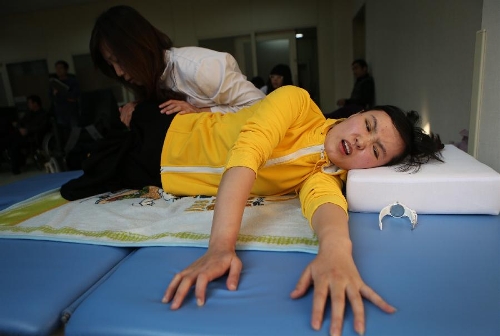 Zhang Lili, a teacher who lost her legs while saving two students from an onrushing bus, does rehabilitative training under the help of a doctor at the China Rehabilitation Research Center in Beijing, capital of China, Jan. 7, 2013. Zhang, who successfully pushed the students out of the harm's way but unable to avoid the bus herself and lost her legs in the accident, has been receiving rehabilitative treatment here for over 4 months. Zhang makes great efforts now in order to be able to walk again. (Xinhua/Jin Liwang) 