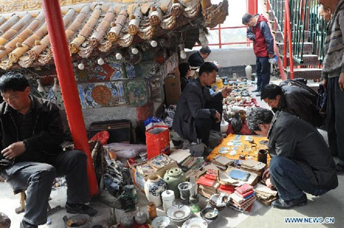 Customers choose curios at a flea market in Zhengzhou, capital of central China's Henan Province, April 14, 2012. The flea market of Zhengzhou Antique Market attracted many collectors everyday. Venders lay their goods on the ground, making the flea market a popular place for curios and antiques business. Photo: Xinhua