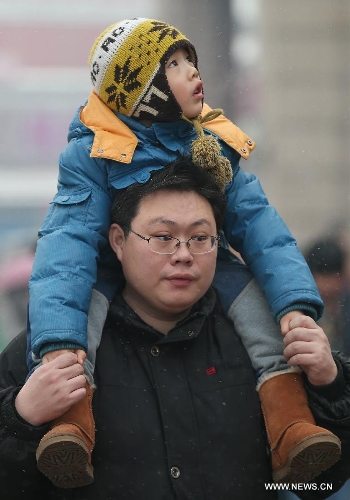 A child sitting on the father's shoulders looks at snow at the Beijing train station in Beijing, capital of China, Feb. 3, 2013. Many children travel with their families during the 40-day Spring Festival travel rush which started on Jan. 26. The Spring Festival, which falls on Feb. 10 this year, is traditionally the most important holiday of the Chinese people.Public transportation is expected to accommodate about 3.41 billion travelers nationwide during the holiday, including 225 million railway passengers. (Xinhua/Jin Liwang)