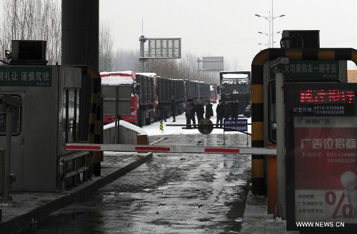 Drivers stand outside the entrance of the Beijing-Kunming Expressway to wait for traffic reopening in Tangxian County, north China's Hebei Province, Jan. 20, 2013. Snow fell in most parts of Hebei Province on Jan. 19 evening and 19 expressways in the province have been closed. (Xinhua/Zhu Xudong)