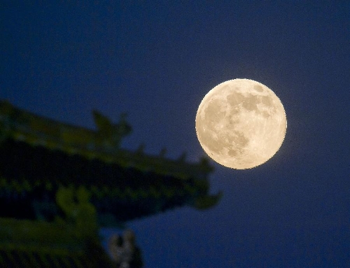 A full moon sets behind a building of the Forbidden City in Beijing, capital of China, June 23, 2013. The moon looks 14 percent larger and 30 percent brighter than usual on Sunday. The scientific term for the phenomenon is 