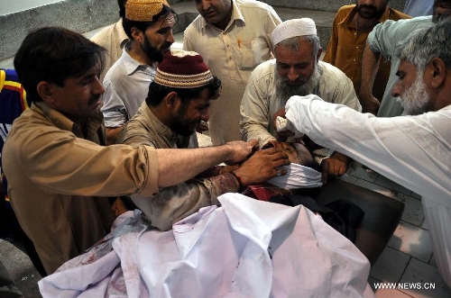 Pakistanis gather around the body of Sadiq Zaman Khattak, a candidate for a National Assembly seat of the ethnic Pashtoon 