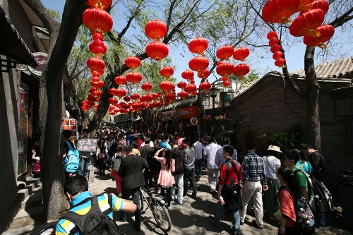 The Nanluoguxiang Hutong has become a must-go spot for tourists(Photo: CRIENGLISH.com/ Wang Zhi)A Hutong is a traditional alley, characteristic of an old Beijing city. A total of 7000 Hutongs have been built throughout the capital in straight lines under strict construction guildlines. The longest Hutong starts from the Beijing Legation Quarter, Dong Jiao Min Xiang,to the Xijiao Min Xiang, and has a total length of 6.5 kilometers, while the shortest Hutong is One-inch Street at only several meters' long. The narrowest Hutong is only about 0.7 meters wide. Therefore, people carrying even a little bit of extra weight have to hold their breath to pass through it. Formed during the Yuan, Ming and Qing, dynasties thousands of Hutongs surround the supreme Imperial Palace from all directions. They are woven into the fabric of people's daily lives.