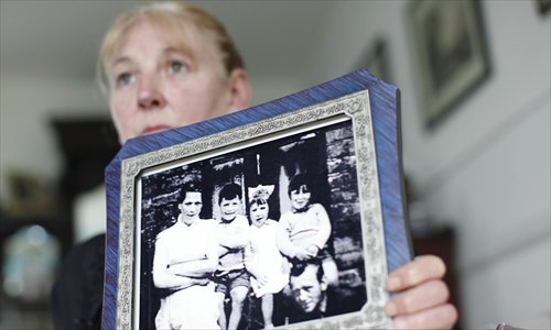 Helen McKendry, eldest daughter of murdered IRA victim Jean McConville, holds a photo showing her mother (left), herself (second right) and members of their family at her home in Northern Ireland on Saturday. Photo: AFP