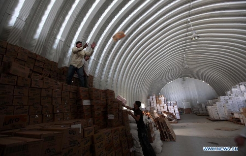 Members of the Red Crescent Society of the United Arab Emirates (UAE) and Syrian refugee workers unload relief materials inside a warehouse at the Mrajeeb Al Fhood refugee camp, 20 km (12.4 miles) east of the city of Zarqa, April 29, 2013. The Mrajeeb Al Fhood camp, with funding from the United Arab Emirates, has received about 2500 Syrian refugees so far, according to the Red Crescent Society of the UAE. (Xinhua/Mohammad Abu Ghosh) 