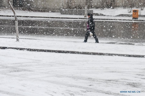 A citizen walks in snow in Baishan City, northeast China's Jilin Province, April 9, 2013. (Xinhua/Zhang Nan) 