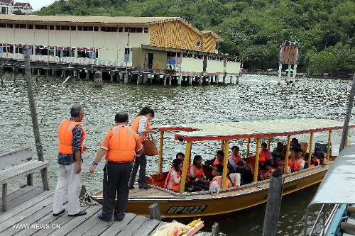 Visitors and reporters get on board a boat in the Water Village in Brunei's capital city Bandar Seri Begawan, April 24, 2013. Dubbed as Venice of the East and situated along the Brunei River, Kampong Ayer is the world's largest water village, sheltering about 30,000 inhabitants. It covers an area of 2.6 square kilo-meters and consists of 10 villages whose building are constructed on the Brunei River. (Xinhua/Li Peng) 