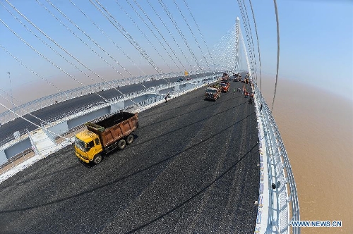 Workers pave asphalt on the surface of the Jiaxing-Shaoxing Sea-crossing Bridge in Shaoxing, east China's Zhejiang Province, May 24, 2013. The bridge is expected to be open to traffic by the end of June this year. It will halve the driving time from Shaoxing to Shanghai in east China after it is finished. (Xinhua/Xu Yu) 