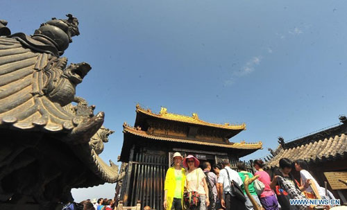 Visitors pose for photos on the Wudang Mountain in central China's Hubei Province July 11, 2012. As the cradle of the Taoist culture, the Wudang Mountain was inscribed on the list of World Cultural Heritages in 1994. The scenery of the mountain attracts tens of thousands of visitors every year. Over 4 million tourists from at home and abroad are expected to visit the site this year. Photo: Xinhua