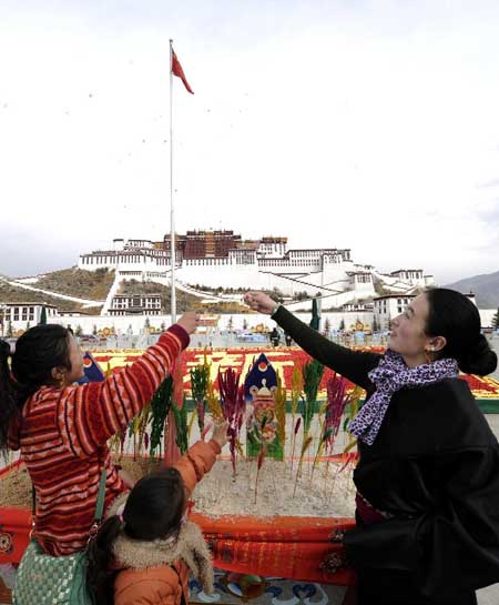 Girls of Tibetan ethnic group worship in front of a container with crops symbolizing harvest at the square of Potala Palace in Lhasa, capital of southwest China's Tibet Autonomous Region, Feb. 17, 2012. Local people were to embrace the upcoming Tibetan New Year, which falls upon Feb. 22 this year. Photo:Xinhua