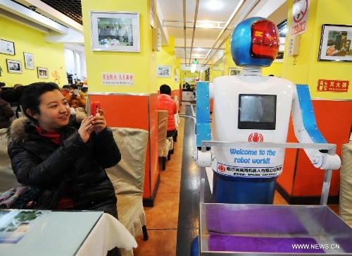 A customer takes pictures of a robot serving dishes in a robot themed restaurant in Harbin, capital of northeast China's Heilongjiang Province, Jan. 18, 2013. Opened in June of 2012, the restaurant has gained fame by using a total of 20 robots to cook meals, deliver dishes and greet customers. (Xinhua/Wang Jianwei) 