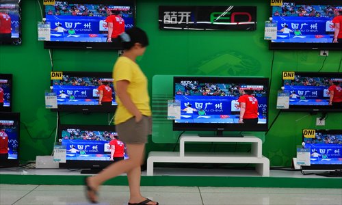 A woman walks past TVs displayed in a store in Beijing Monday. Sales of China's smart TVs in the first six months have reached 4.57 million sets, up 105.7 percent compared with one year earlier, the China Smart Multimedia Terminal Technology Association said in a recent report. Sales of smart TVs accounted for 45 percent of total TV sales from January to June, the report said. Photo: IC