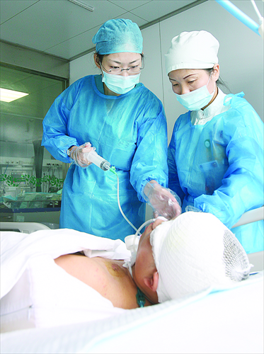 Yang feeds a patient with a tube under the instruction of a nurse. Photo: IC