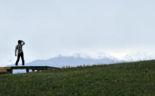 A tourist visits a grassland in the Yugur Autonomous County of Sunan, Northwest China's Gansu Province, July 23, 2012. Gansu's Sunan County has become a populous tourists site in recent years, boasting its diversified scenic view, including snow mountains, grasslands, valleys, deserts and lakes. 