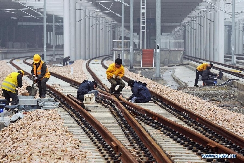 Construction workers and engineers examine rail tracks in the Huzhou Railway Station in Huzhou, east China's Zhejiang Province, Feb. 26, 2013. The 150-kilometer Hangzhou-Ningbo high-speed railway linking Hangzhou and Ningbo, two hub cities in Zhejiang, commenced its integration test here on Friday. Once put into operation on July 2013 as expected, the high-speed railway that designed at a top speed of 350km/h, would reduce the travel time to 36 minitues, a quarter time of the current two-hour journey. (Xinhua/Tan Jin)  