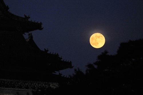 A full moon sets behind a building of the Forbidden City in Beijing, capital of China, June 23, 2013. The moon looks 14 percent larger and 30 percent brighter than usual on Sunday. The scientific term for the phenomenon is 