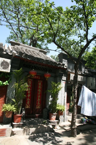 The gate to the quadrangle courtyard(Photo: CRIENGLISH.com/ Wang Zhi)A Hutong is a traditional alley, characteristic of an old Beijing city. A total of 7000 Hutongs have been built throughout the capital in straight lines under strict construction guildlines. The longest Hutong starts from the Beijing Legation Quarter, Dong Jiao Min Xiang,to the Xijiao Min Xiang, and has a total length of 6.5 kilometers, while the shortest Hutong is One-inch Street at only several meters' long. The narrowest Hutong is only about 0.7 meters wide. Therefore, people carrying even a little bit of extra weight have to hold their breath to pass through it. Formed during the Yuan, Ming and Qing, dynasties thousands of Hutongs surround the supreme Imperial Palace from all directions. They are woven into the fabric of people's daily lives.