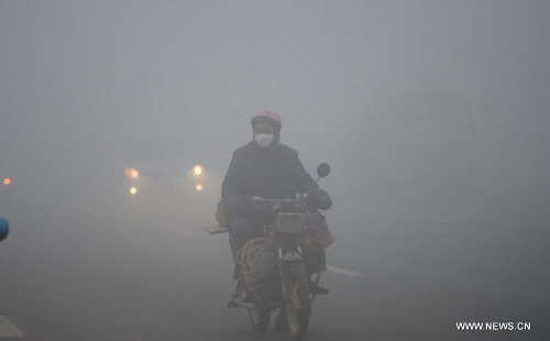 A citizen rides amid dense fog in Nanchang City, capital of east China's Jiangxi Province, Jan. 12, 2013. A fog hit many parts of Jiangxi on Saturday. (Xinhua/Zhou Ke)  