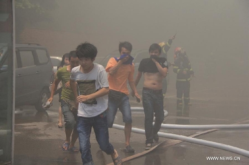 People evacuate from a burning four-story commercial building in Liuzhou, south China's Guangxi Zhuang Autonomous Region, July 1, 2013. Twelve fire trucks and 49 firefighters have been dispatched to fight the blaze. No casualties have been reported thus far. (Xinhua) 