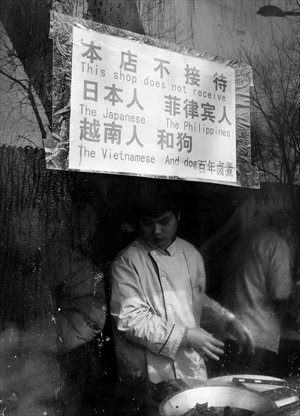 A cook works in a restaurant behind a sign that says 