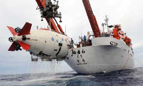 Technicians transfer China's manned submersible Jiaolong to its mother ship Xiangyanghong-9 in Pacific Ocean, June 30, 2012. The Jiaolong have succeeded in reaching 7,035 meters below sea level during its sixth and last dive in the Mariana Trench Saturday. Photo: Xinhua