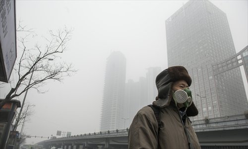 A man wearing a mask walks along a smog-shrouded street in Beijing, the capital of China, on January 29, 2013. The National Meteorological Center (NMC) issued a code-blue alert on January 27 as the smoggy weather forecast for the following two days would cut visibility and worsen air pollution in some central and eastern Chinese cities. Photo: Li Hao/GT