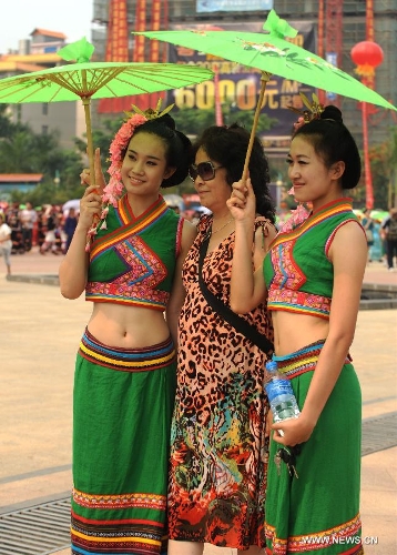   A visitor poses for photo with girls of Dai ethnic group who perform a traditional umbrella dance to celebrate the Water Splashing Festival, also the New Year of the Dai ethnic group, in Jinghong City, Dai Autonomous Prefecture of Xishuangbanna, southwest China's Yunnan Province, April 14, 2013. (Xinhua/Qin Qing)  