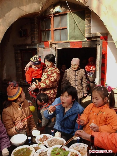  A family gather to have a family-reunion dinner outside their cave dwelling in Qucun Village of Shaanxian County, central China's Henan Province, Feb. 1, 2003. Different from the other parts of China in which people have family reunion dinner on the Chinese New Year's eve, people living in the central China region have the family banquet at the noon of the first day of the lunar month. Chinese people who live in the central China region have formed various traditions to celebrate the Chinese Lunar New Year. (Xinhua/Wang Song)