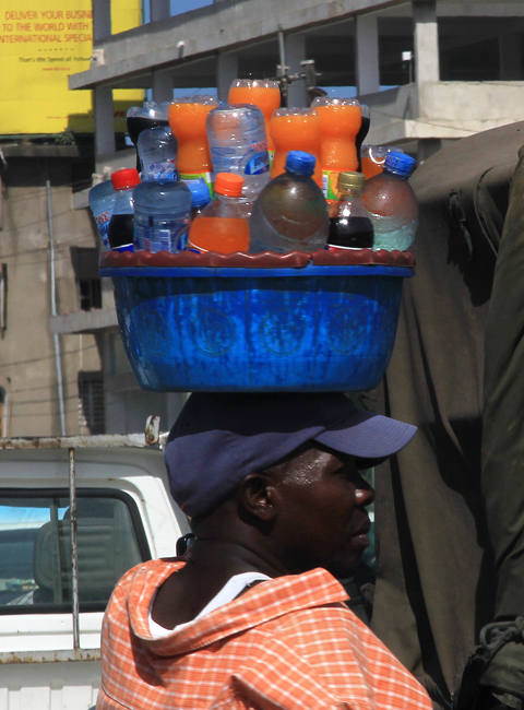 A vendor walks along the street with a basin of soft drinks on his head in Dar es Salaam, Tanzania on February 13, 2013. Photo: Zhu Liangliang/GT