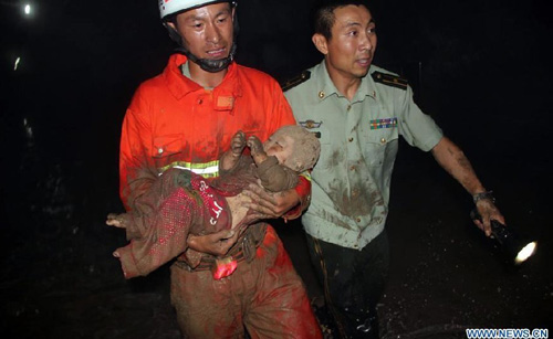 A firefighter rescues a child from an accident site after a road collapsed at Liaoyang street of Harbin city, Northeast China's Heilongjiang Province, August 14, 2012. Two people were confirmed dead and two others injured when a roadbed collapsed at Liaoyang Street in Nangang district of Harbin city on Tuesday. Photo: Xinhua