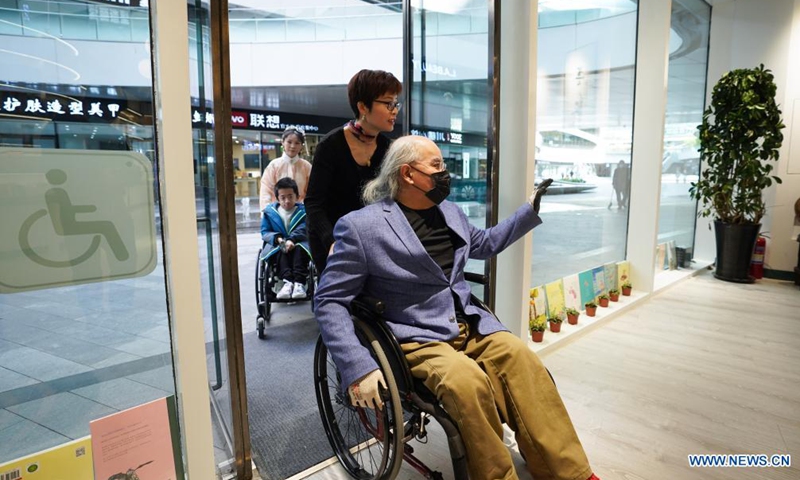 Disabled reader Liu Shijie (front) is wheelchaired into Shanyuan Book Chamber in Beijing, capital of China, April 14, 2021.Photo:Xinhua