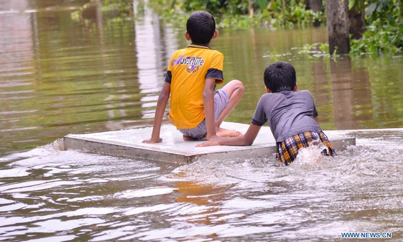 Boys are seen on a flooded road in Gampaha, Sri Lanka, May 15, 2021. At least four people had died and over 42,000 others had been affected by days of strong winds and heavy rains which lashed the country due to the formation of a super cyclone in the Bay of Bengal, Sri Lanka's Disaster Management Center (DMC) said in its latest weather report Saturday.(Photo: Xinhua)