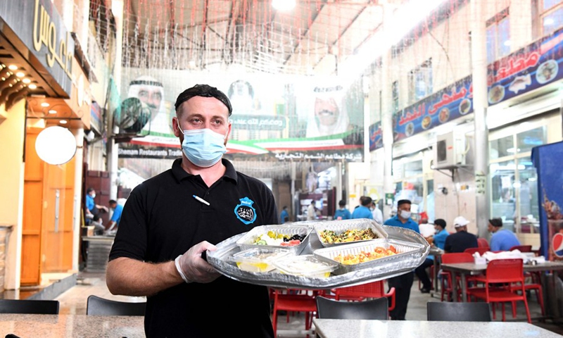 A worker of a Kuwaiti restaurant serves food for customers at the Al-Mubarakiya market in Kuwait City, Kuwait, May 23, 2021. (Photo: Xinhua)