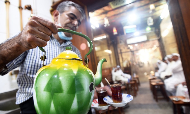 A worker serves tea for customers in a cafe at the Al-Mubarakiya market in Kuwait City, Kuwait, May 23, 2021.(Photo: Xinhua)