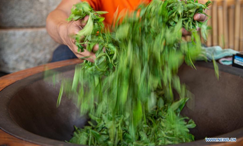 A worker stirs and roasts fresh tea leaves at Wulilu tea garden in Baisha Li Autonomous County in south China's Hainan Province, June 9, 2021. (Xinhua/Pu Xiaoxu)